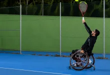 Wheelchair Tennis Player in a Black Outfit Serves a Bright Yellow green Tennis Ball on a Blue Court with a Chain link Fence Behind Zaragozala | Agenda Cultural Ocio Y Planes En Zaragoza Página 189 Zaragozala Qué Hacer En Zaragoza