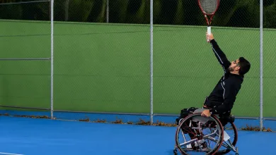 Wheelchair Tennis Player in a Black Outfit Serves a Bright Yellow green Tennis Ball on a Blue Court with a Chain link Fence Behind Zaragozala | Agenda Cultural Ocio Y Planes En Zaragoza Zaragozala   Qué Hacer En Zaragoza