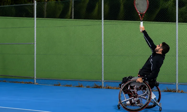Wheelchair Tennis Player in a Black Outfit Serves a Bright Yellow green Tennis Ball on a Blue Court with a Chain link Fence Behind Zaragozala | Agenda Cultural Ocio Y Planes En Zaragoza Zaragozala Qué Hacer En Zaragoza