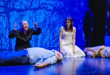 Two Actors on a Blue lit Stage Kneel Beside Motionless Bodies As a Woman in Black Gestures Dramatically While a Woman in a White Dress Looks On Zaragozala | Agenda Cultural Ocio Y Planes En Zaragoza Zaragozala Qué Hacer En Zaragoza