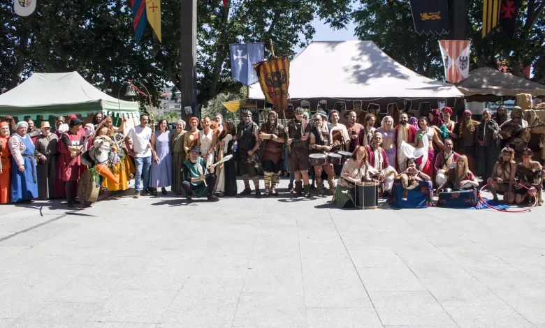 Large Group of People in Medieval Costumes Posing Outdoors at a Festival with Tents and Colorful Banners Behind Them Comienza El Mercado Medieval De Zaragoza 2026 Zaragozala Qué Hacer En Zaragoza