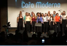 Group of Singers on a Lit Stage Performing with Microphones Conductor on the Left Audience Visible in the Foreground Zaragozala | Agenda Cultural Ocio Y Planes En Zaragoza Zaragozala   Qué Hacer En Zaragoza