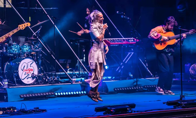 Female Singer Mid jump Microphone in Hand Performing on a Blue lit Stage with a Guitarist on the Right and a Drummer on the Left in the Background Chambao Y Lia Kali Llenan Pirineos Sur 2026 Zaragozala   Qué Hacer En Zaragoza