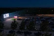 Drive in Movie Theater at Night with a Bright Screen on the Left a Pink Food Truck Nearby and Rows of Parked Cars Under Dim Streetlights Zaragozala | Agenda Cultural Ocio Y Planes En Zaragoza Zaragozala   Qué Hacer En Zaragoza