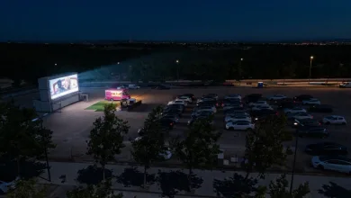 Drive in Movie Theater at Night with a Bright Screen on the Left a Pink Food Truck Nearby and Rows of Parked Cars Under Dim Streetlights Puerto Venecia Abre Este Sábado Un Autocine De Verano Zaragozala   Qué Hacer En Zaragoza