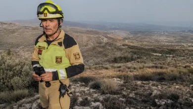 Firefighter in Tan Turnout Gear and Yellow Helmet Stands on Rocky Hillside Overlooking a Dry Valley Incendio Forestal Ejulve Bomberos Zaragoza Apoyan Evacuación Zaragozala Qué Hacer En Zaragoza