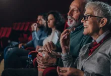 Smiling Elderly Woman with Short White Hair and Glasses Eats Popcorn in a Movie Theater Seated with Others in Red Seats Zaragozala | Agenda Cultural Ocio Y Planes En Zaragoza Zaragozala   Qué Hacer En Zaragoza