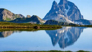 Snow capped Mountain Reflected in a Calm Alpine Lake with Green Meadow in Foreground Ibones De Anayet Multas Por Acampar Y Bañarse Zaragozala Qué Hacer En Zaragoza