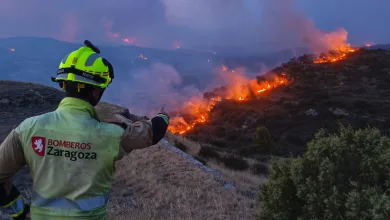 Firefighter in a Yellow Helmet and Jacket Overlooking a Wildfire on a Hillside with Smoke and Flames in the Distance zaragoza Firefighters Los Bomberos De Zaragoza Se Suman Al Operativo Del Incendio De Orés Zaragozala Qué Hacer En Zaragoza