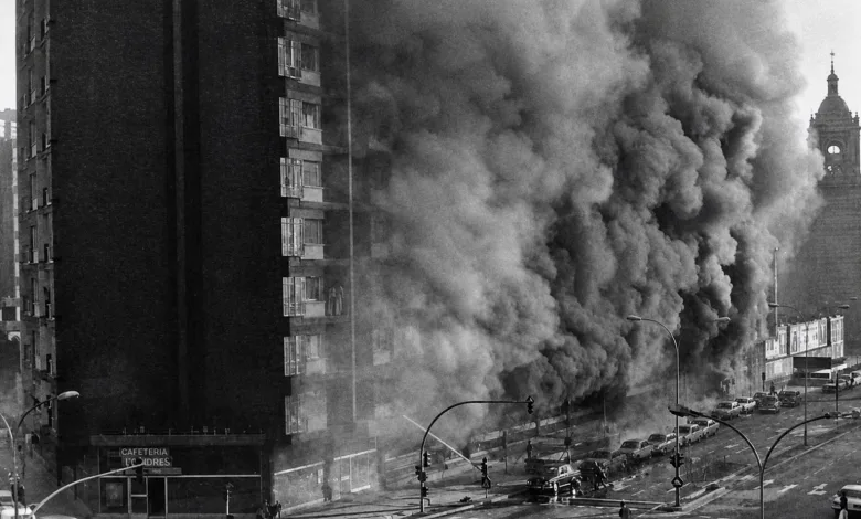 Massive Plume of Dark Smoke Rising from a Fire Along a City Street Beside a Tall Apartment Building with Cars and Pedestrians Nearby Zaragoza Recuerda a Las Víctimas Del Hotel Corona De Aragón Zaragozala Qué Hacer En Zaragoza
