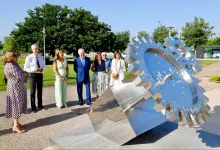 Group of Seven Adults in Smart Attire Standing Near a Large Stainless Steel Gear Sculpture in a Park on a Sunny Day Looking at It Zaragozala | Agenda Cultural Ocio Y Planes En Zaragoza Zaragozala Qué Hacer En Zaragoza