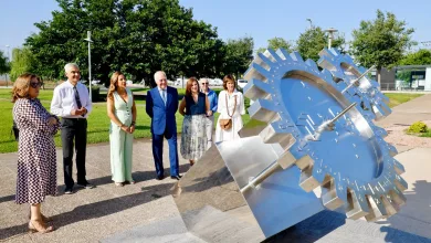 Group of Seven Adults in Smart Attire Standing Near a Large Stainless Steel Gear Sculpture in a Park on a Sunny Day Looking at It Zaragozala | Agenda Cultural Ocio Y Planes En Zaragoza Zaragozala   Qué Hacer En Zaragoza