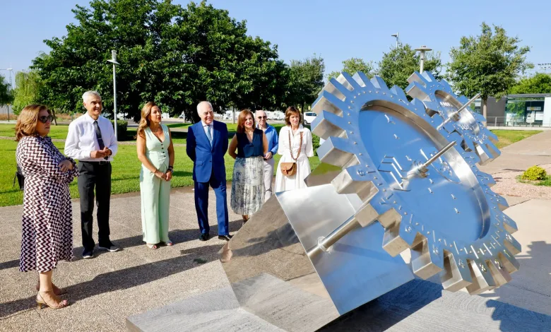 Group of Seven Adults in Smart Attire Standing Near a Large Stainless Steel Gear Sculpture in a Park on a Sunny Day Looking at It Zaragozala | Agenda Cultural Ocio Y Planes En Zaragoza Zaragozala Qué Hacer En Zaragoza