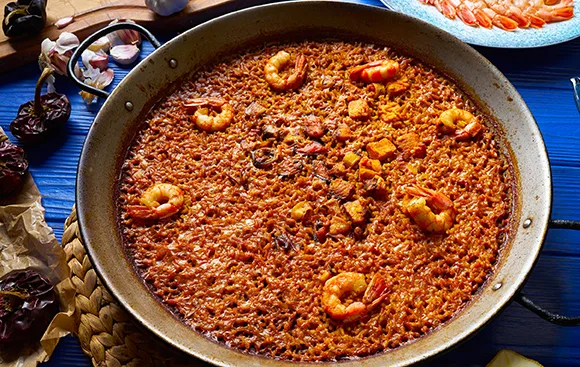 Pan of Seafood Paella with Shrimp Scattered over Saffron tried Rice in a Large Skillet on a Blue Table Surface Dónde Comer Arroz Del Señorito En Zaragoza Zaragozala Qué Hacer En Zaragoza