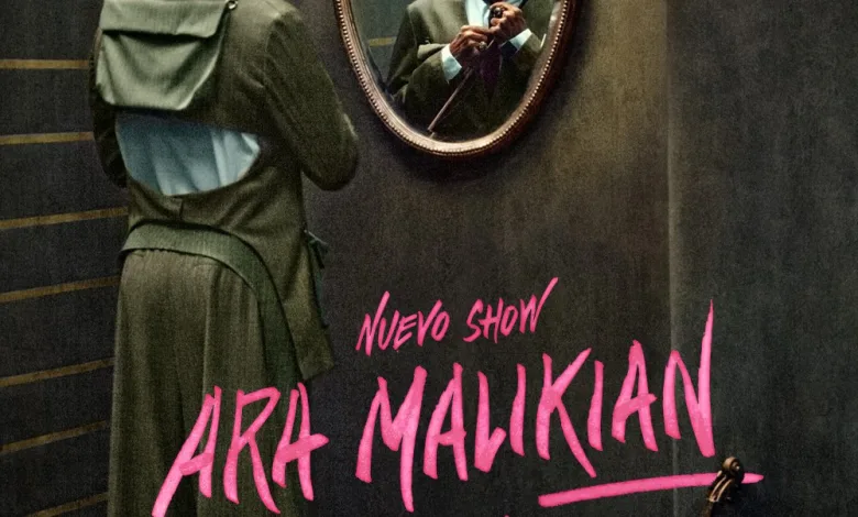 Man in a Green Coat Adjusts His Tie While Facing an Ornate Wall Mirror a Violin Rests on the Floor Beside a Bold Pink Poster That Reads art Malikian Intruso Zaragozala | Agenda Cultural Ocio Y Planes En Zaragoza Zaragozala Qué Hacer En Zaragoza