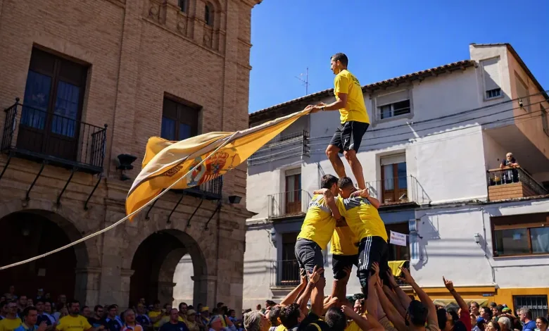 Men in Yellow Shirts Form a Multi person Human Tower As the Top Climber Holds a Flag in a Sunny Street Festival Castillos Humanos De Ateca Cuándo Y Dónde Verlos Zaragozala Qué Hacer En Zaragoza