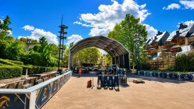 Open air Stage with a Curved Metal Canopy Tall Lighting Rigs and Stacks of Blue Chairs Under a Bright Blue Sky El Fiestón Del Verano Jaca 2026 Queda Cancelado Zaragozala Qué Hacer En Zaragoza