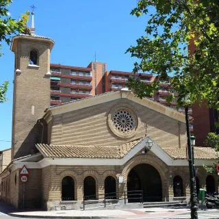 Stone Church with a Circular Rose Window and Arched Entry Flanked by a Small Bell Tower on the Left on a Tree lined Urban Street Fiestas De Santa Isabel 2026 Programa Y Horarios Zaragozala Qué Hacer En Zaragoza