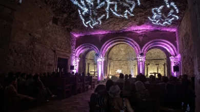 Live Music Performance in a Historic Stone Hall with Purple lit Arches and an Audience Seated Along Wooden Pews on Both Sides El Ciclo música En La Roca Regresa a San Juan De La Peña Con Tres Conciertos En Agosto Zaragozala Qué Hacer En Zaragoza