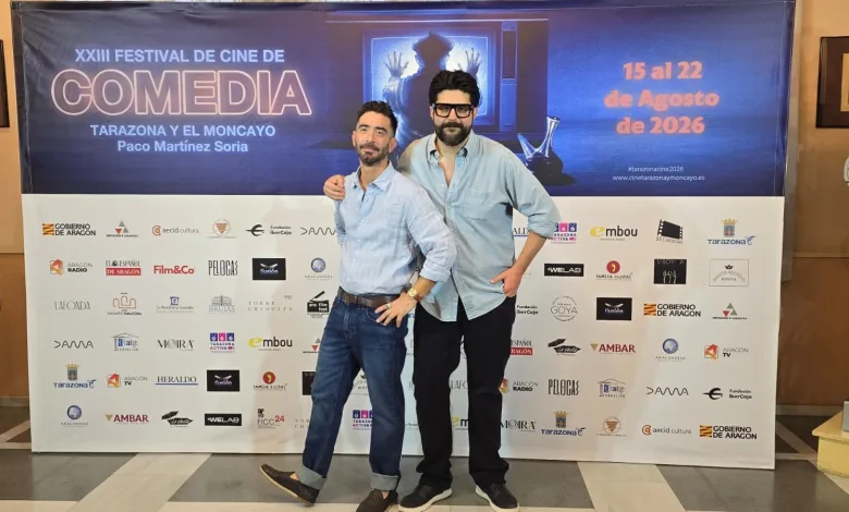 Two Men in Light Blue Shirts Pose with an Arm Around Each Other in Front of a Large Film Festival Banner Reading xxiii Festival De Cine De Comedia in Tarazona Y El Moncayo 2026 Poster Behind Them Tarazona Cine Recibe a Raúl Campos Y Octavio Hinojosa Zaragozala Qué Hacer En Zaragoza