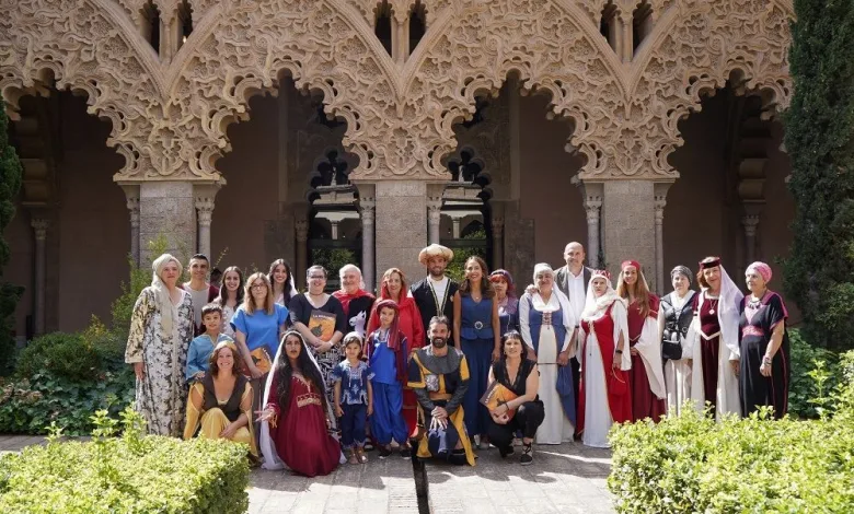 Group of People in Colorful Medieval Costumes Posing in Front of an Ornate Stone Archway in a Sunlit Courtyard La Morisma De Aínsa 2026 Fecha Y Horarios Zaragozala Qué Hacer En Zaragoza