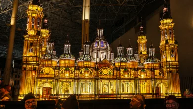 Illuminated Ornate Cathedral Model on Display with Golden Glow and Visitors in the Foreground