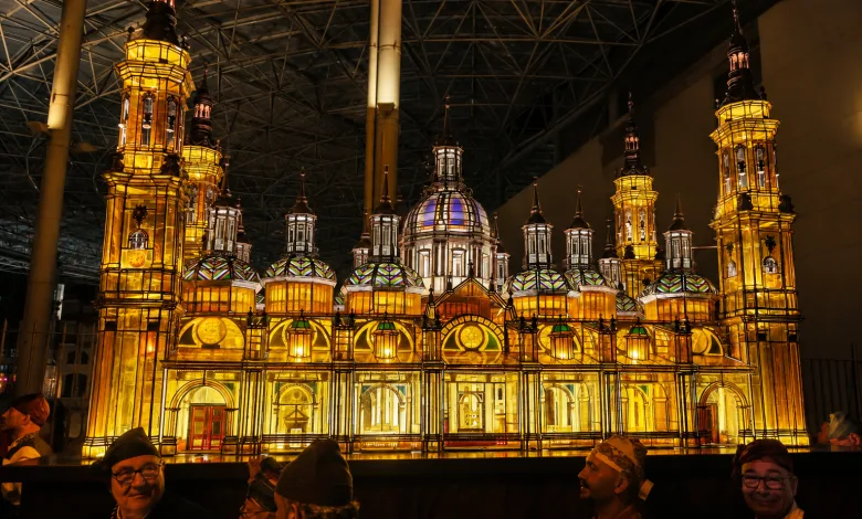 Illuminated Ornate Cathedral Model on Display with Golden Glow and Visitors in the Foreground