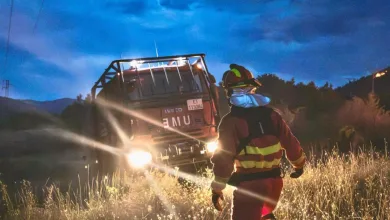 Firefighter in Reflective Gear and Helmet Stands in Tall Grass As a Tilted Fire Truck Glows with Headlights at Nightfall Muere Un Militar De La Ume En El Incendio De Riglos Zaragozala   Qué Hacer En Zaragoza